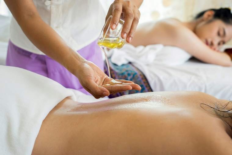 Therapist pouring warm massage oil during a full body massage